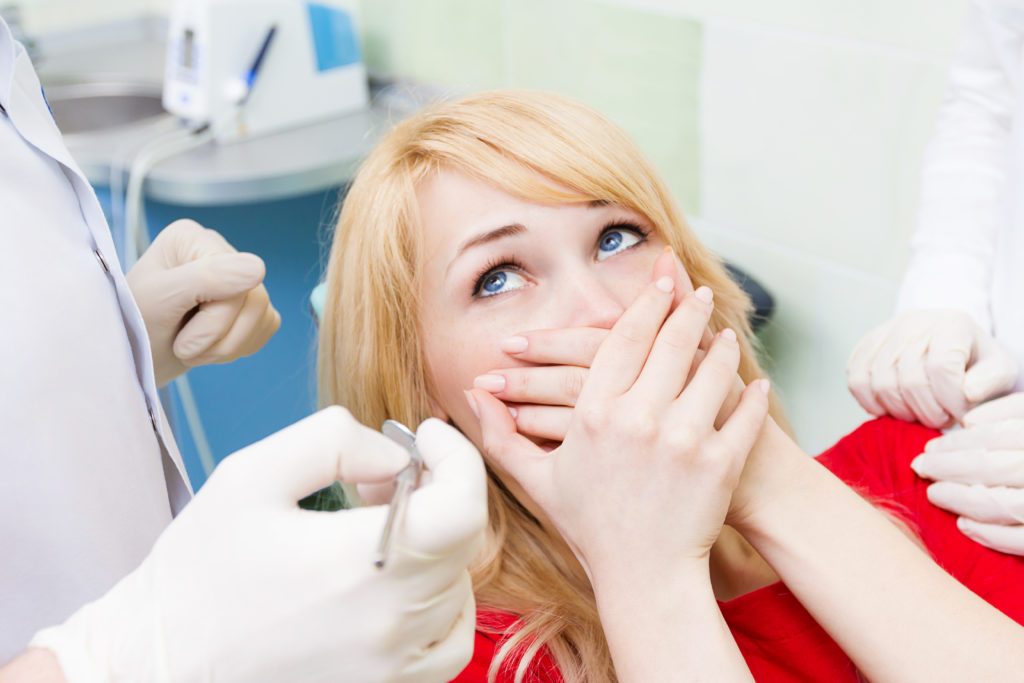 Female patient in dentist office afraid of doctor