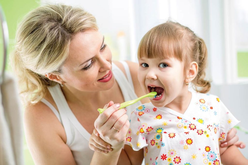 Mother with daughter brushing tooth