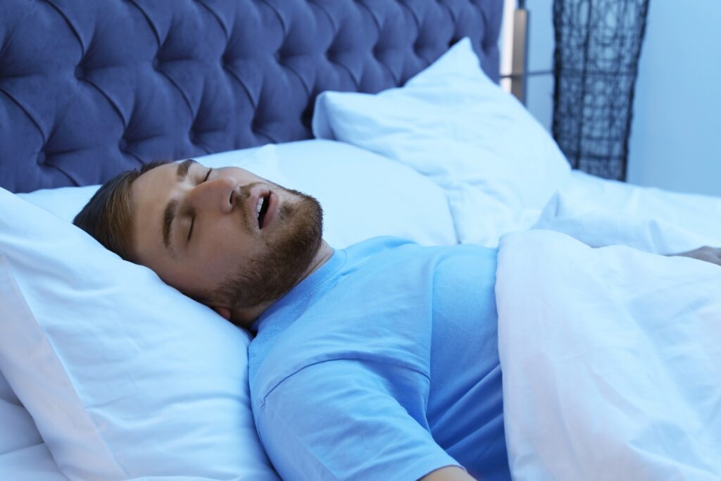 Young man snoring while sleeping in bed at night. Sleep disorder
